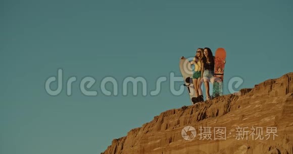 两个性感的女孩在沙漠里拿着沙板
