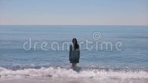 一个穿着湿衣服的漂亮女孩走出波浪状的大海，走向照相机