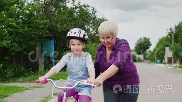 祖母教她孙女如何骑自行车。 儿童的第一次成功，老年活动