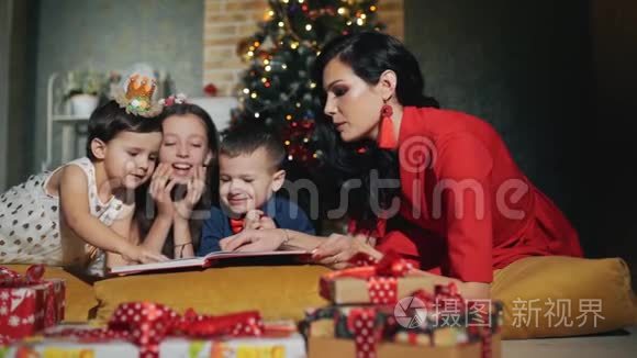 开朗的大家庭四口人正在看书.. 新年之夜在圣诞树脚下