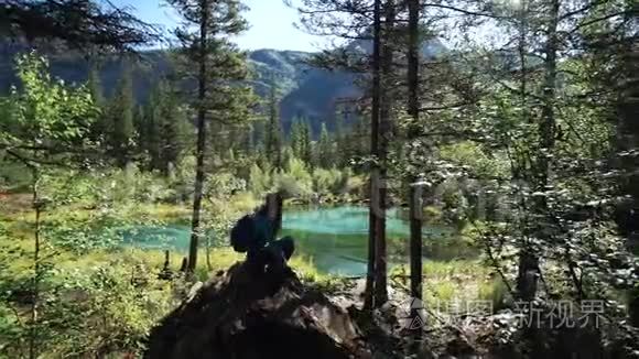 旅行者女孩坐在森林里的一块石头上，正在欣赏美丽的蒙丹湖的风景。