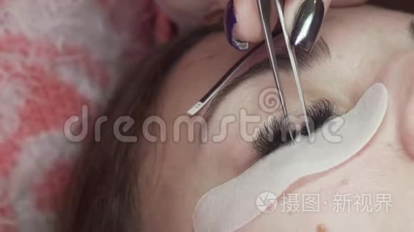 睫毛延伸，化妆师拿着钳子，把人造睫毛贴在女人眼睛上，极端的近距离。