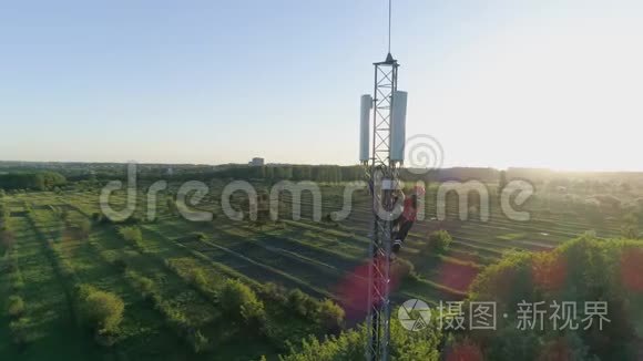 工程师在天线通讯塔上工作，在阳光下展示城市景观背景