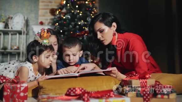 开朗的大家庭四口人正在看书.. 新年之夜在圣诞树脚下