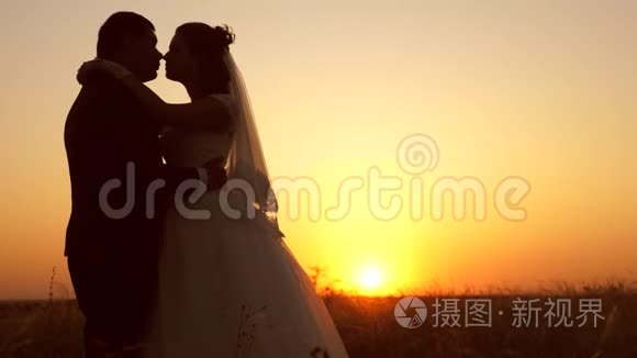 年轻的已婚夫妇在日落时亲吻和拥抱。 男女婚姻生活