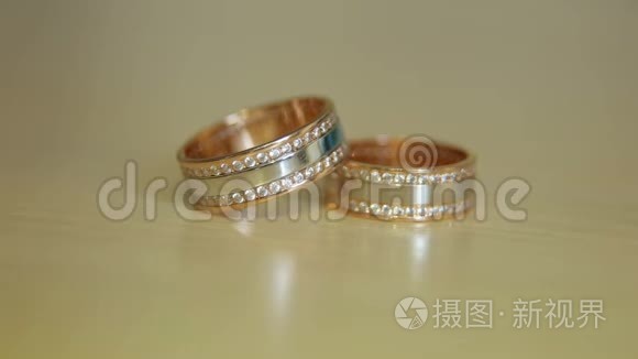 米色背景上的金色订婚戒指。 结婚戒指。