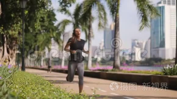 年轻混合种族运动健身女孩跑城市公园和使用智能健身跟踪手表小玩意的心脏锻炼