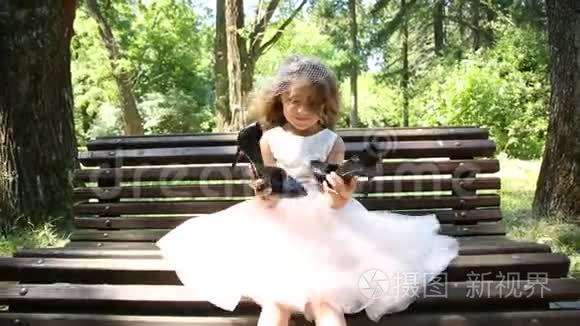 坐在长凳上的小女孩拿着大鞋子视频