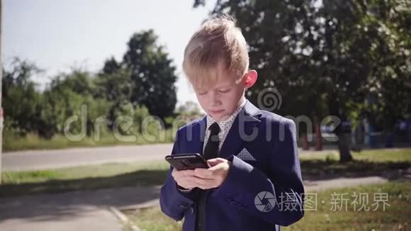 穿西装的小男孩拿着智能手机在街上玩游戏