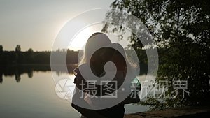 日落时分，一个女人抱着一个小女孩在湖边亲吻她