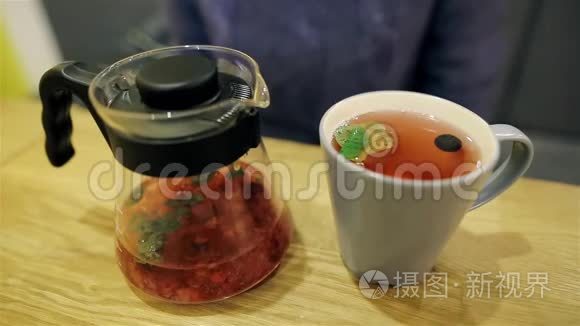 可爱的年轻女孩坐在桌子旁喝茶，暖手。 带蓝莓的斯堪的纳维亚热茶