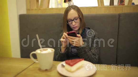 悲伤的女人在咖啡馆里使用智能手机上的应用程序，喝着带棉花糖的热巧克力，在手机上发短信。 同时