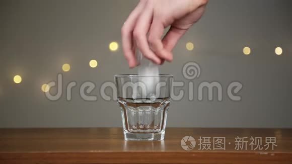 人把冰扔进玻璃杯，然后倒椰子水。 在灯光的背景下