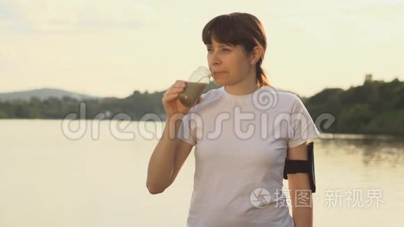 一位年轻女子在湖边训练前后喝排毒冰沙。