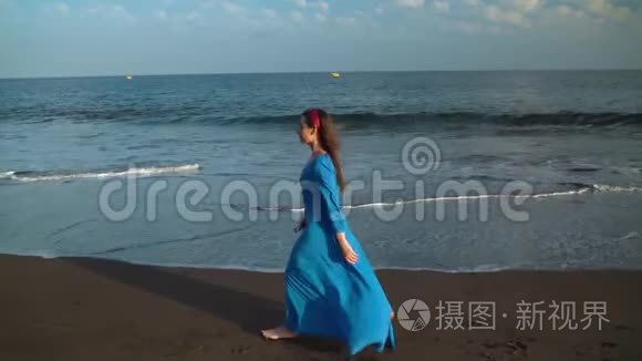 穿着漂亮蓝色裙子的女人走在黑色的火山海滩上