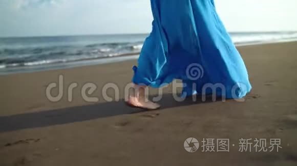 一个穿着漂亮蓝色裙子的女人在黑色火山海滩上行走的腿