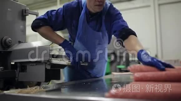 熏香肠的生产和包装过程。 这名工人管理一台自动机器，用于生产