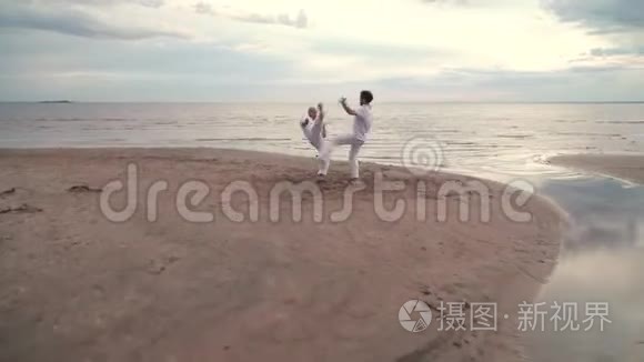 两个人在海滩上练习卡波伊拉视频