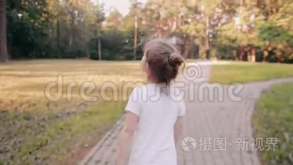 小女孩在公园的路上散步。 一束美丽的头发在阳光下闪闪发光。 慢影，后景