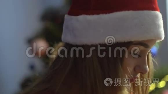 戴着圣诞帽的漂亮年轻女孩在镜头前看着微笑。 圣诞心情