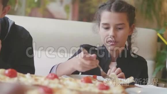 少女在咖啡厅慢动作视频里吃披萨。 孩子们吃比萨饼，吃美味的比萨饼。 与生活方式有关的人