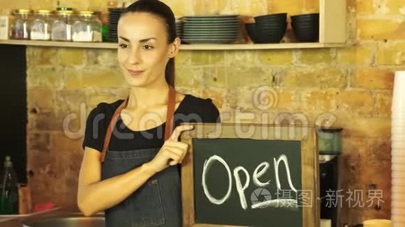 一个咖啡店的工人拿着一个开放的标志。