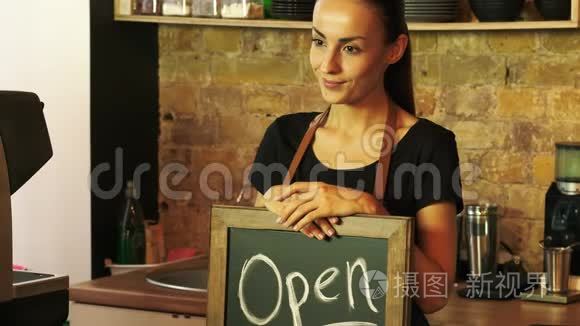 一个咖啡店的工人拿着一个开放的标志。