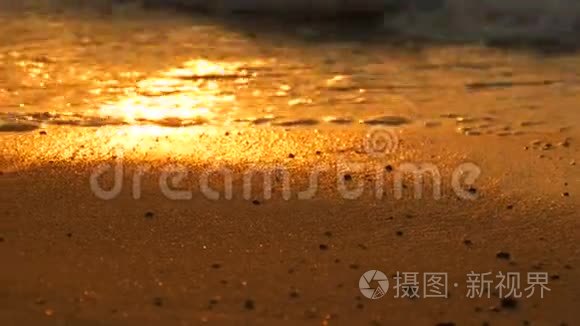 令人惊叹的美丽的红色日落在海滩上。 泰国沙滩上有泡沫的波浪