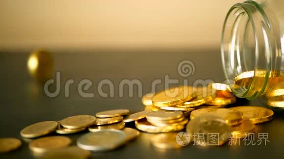 用黑桌上的金币和旋转的便士来特写静止的生活。 黄色的硬币从罐子里掉了出来。