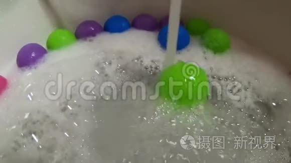 浴缸里的水流滚动着绿色塑料球视频