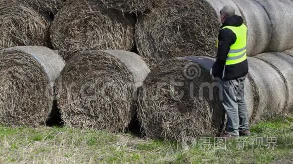 农民检查干草捆和谈论智能手机视频