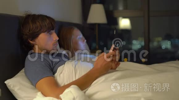 男人和女人躺在床上，每个人都有智能手机和平板电脑。 婚姻和两性关系问题