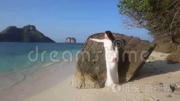 新娘靠在岩石上，看着海滩