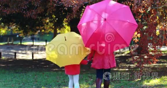 母女俩在伞下一起在公园散步视频