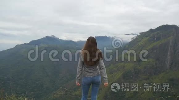 小女孩伸出山顶，举起双手。 站在美丽峡谷边缘的女游客