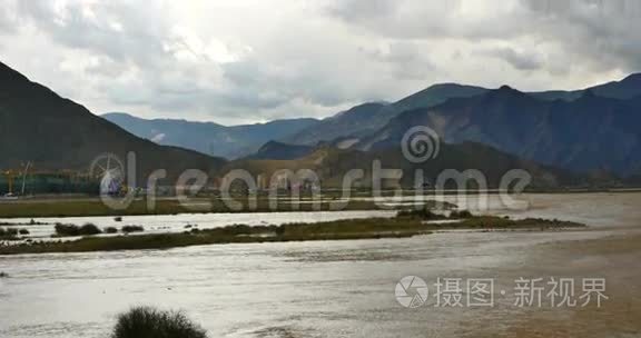 拉萨河与遥远的城市建筑，乌云团团滚过西藏山顶。