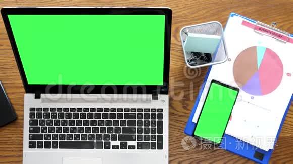 桌面上有绿色屏幕的笔记本电脑和智能手机