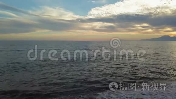 美丽的日落在海滩上，金色的阳光反射在大海和山的背景上