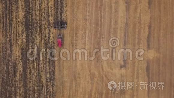 空中：在耕地上向无人机射击。一辆红色拖拉机在秋天开垦田地