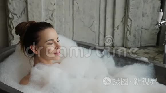 女孩躺在泡沫的大石头浴室里视频