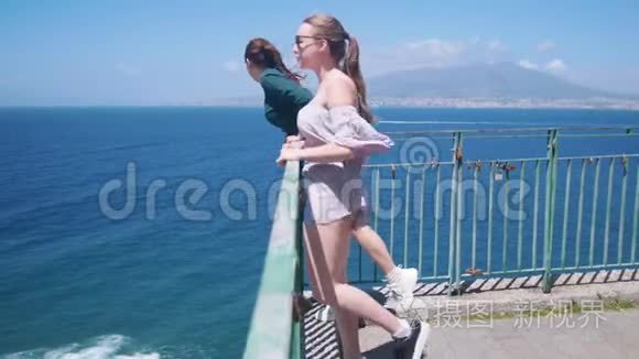 两个年轻快乐的女人站在观察甲板上看着大海