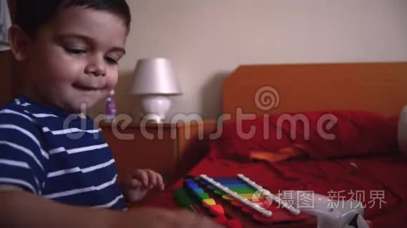 可爱的两岁男孩在卧室里玩木琴视频