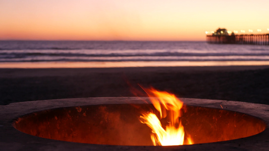 美国加利福尼亚州的篝火坑暮色海滩上的篝火海水波浪下视频