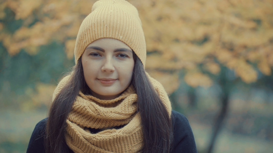 秋天公园里一个漂亮女孩的肖像年轻女人穿着大衣戴着帽子视频