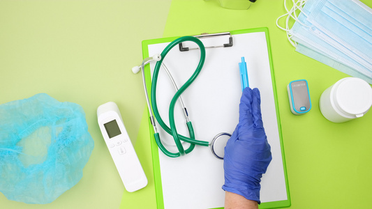 蓝色的乳胶手套将医疗用品放在绿色桌子上一个听诊器温度计视频