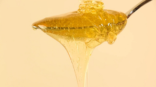 密闭的蜂蜜从米边上的金属勺子流出视频