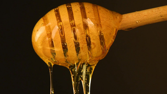 密闭的蜂蜜从黑色的木制黄花中流出视频