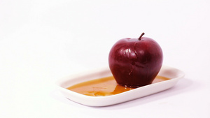 白盘上蜂蜜中的苹果切片以白色背景的蜂蜜和红苹果8秒视频