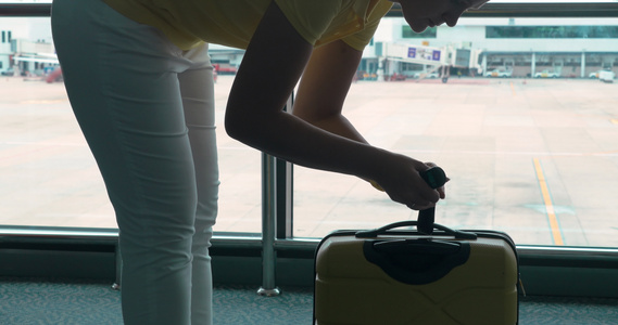 在机场妇女用紧身包装的称重器称行李重量视频