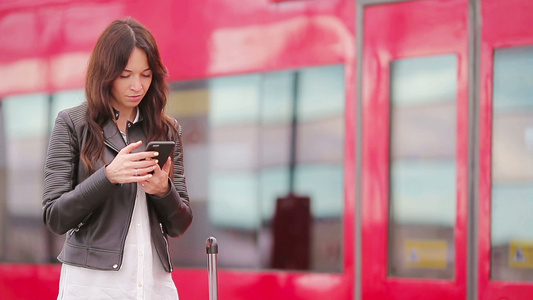 带着行李在火车站看手机的年轻女人高加索游客在旅行时视频